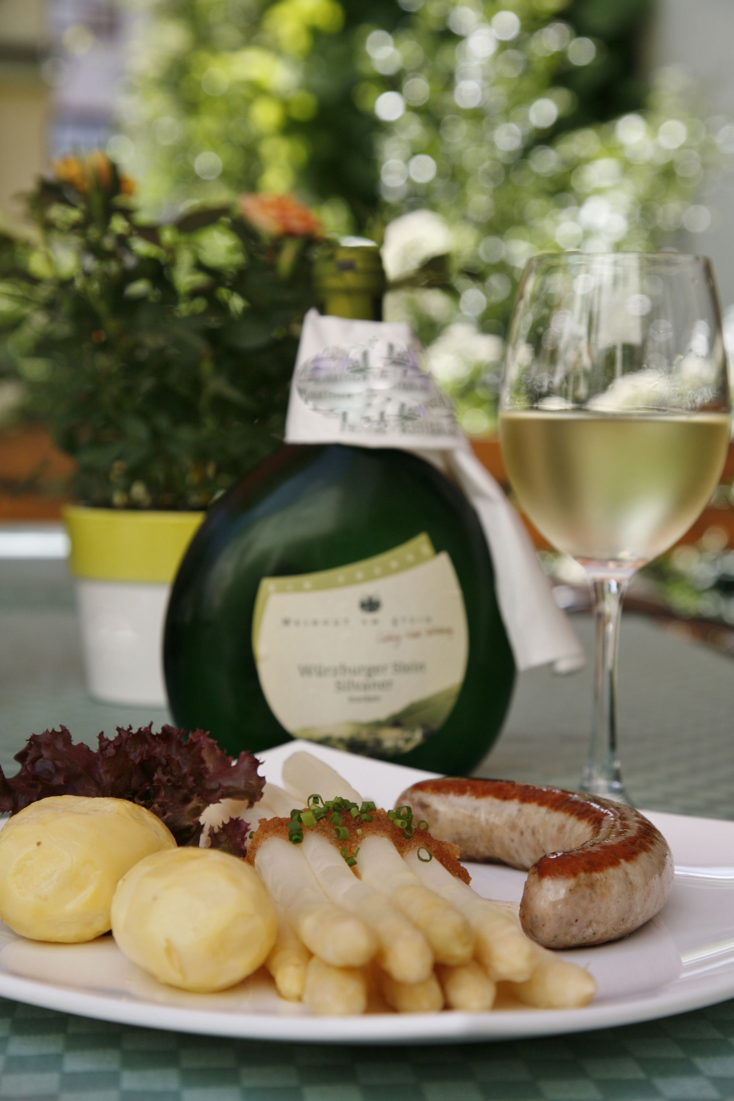 A plate with food and a bottle of wine on a table.