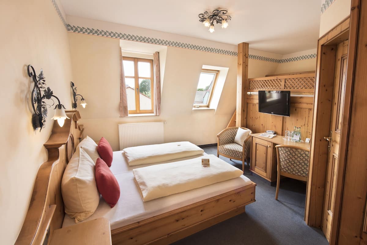 Une chambre à coucher avec un lit en bois, un bureau, une chaise, une télévision et une fenêtre.