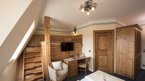 Une chambre avec un espace nuit en mezzanine, un bureau avec une chaise, un téléviseur et des armoires en bois.