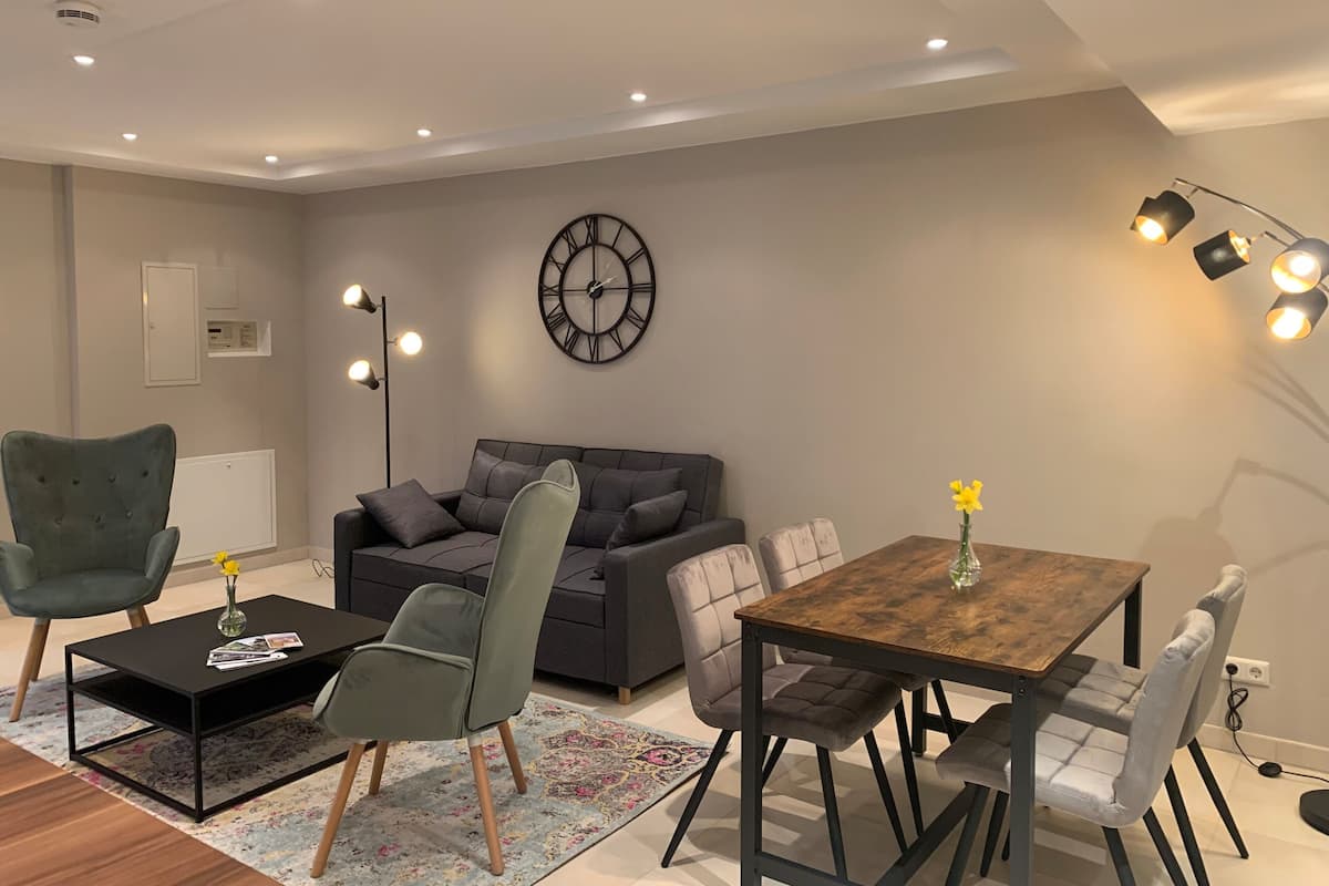 Un salon moderne avec un canapé gris, une table basse en bois et une table à manger avec des chaises.