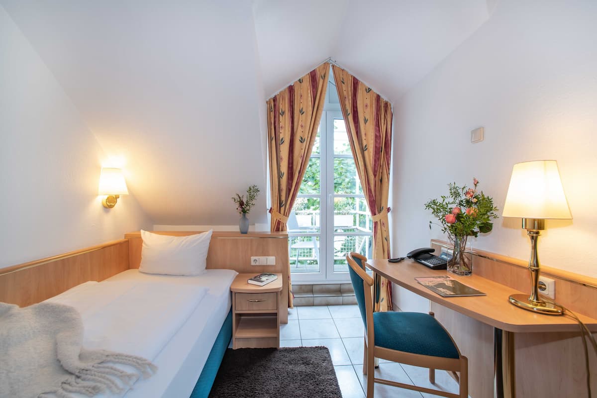 Une chambre d’hôtel avec un lit, un bureau, une chaise et une fenêtre avec des rideaux.