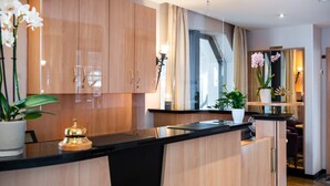 A modern kitchen with wooden cabinets, a black countertop, and potted plants. - UNO Hotel Posthof Saarlouis by ANS (Saarlouis)