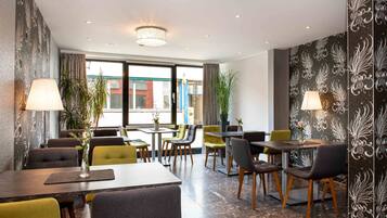 Un comedor moderno con mesas y sillas, plantas en macetas y paneles decorativos en la pared.