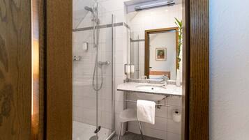 A modern bathroom with a glass-enclosed shower, a granite countertop sink, and a white towel hanging on a rack.