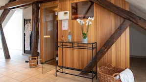 A wooden interior with a wooden-framed ceiling, a small table with a vase of white flowers, and a wicker basket. - UNO Hotel Posthof Saarlouis by ANS (Saarlouis)