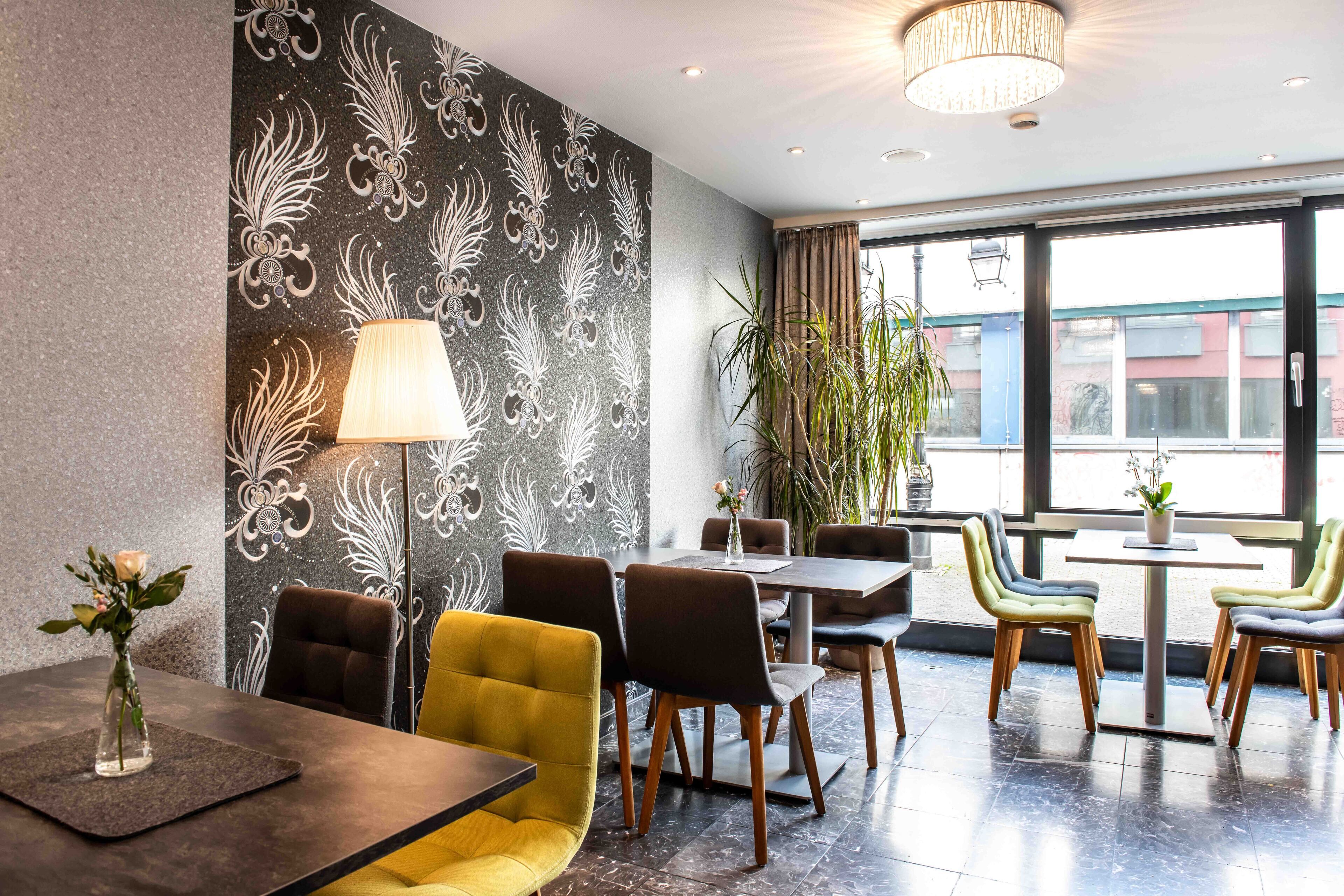 Ein moderner Essbereich mit einer Wand in Schwarzweiß-Muster, einem gelben Sofa und einem Tisch mit einem Blumenarrangement.