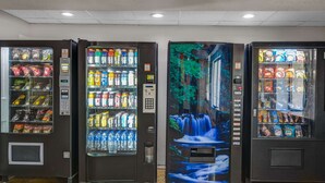 Trois distributeurs automatiques proposant une variété de boissons et d’en-cas.