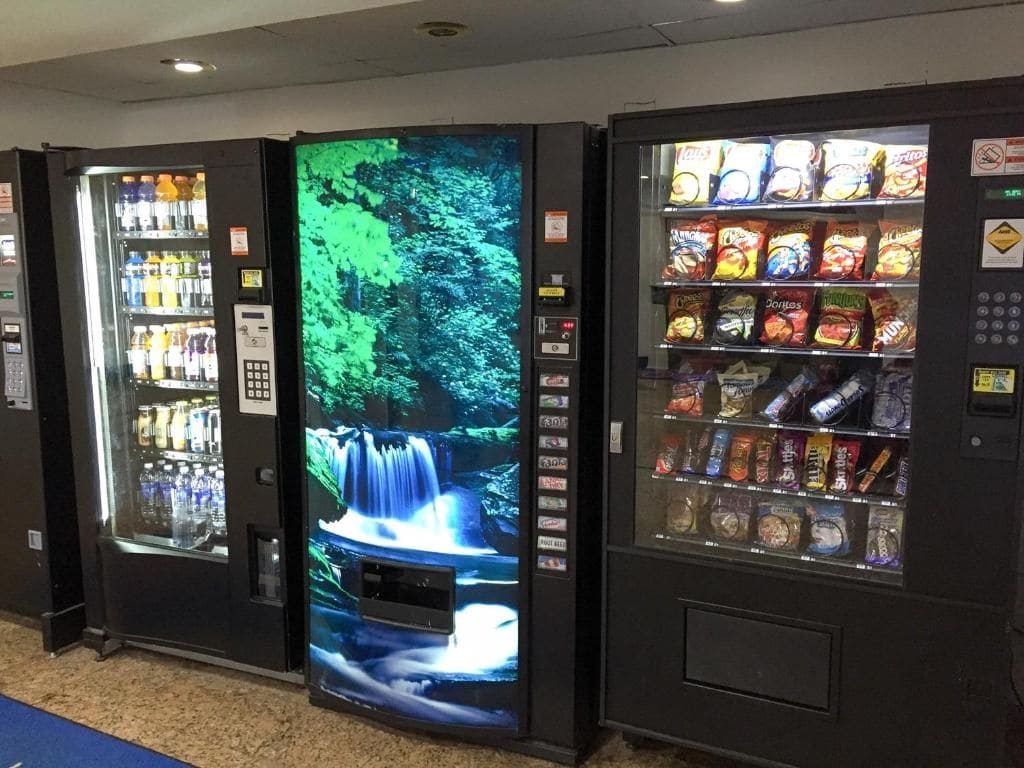 A row of vending machines with various snacks and beverages.
