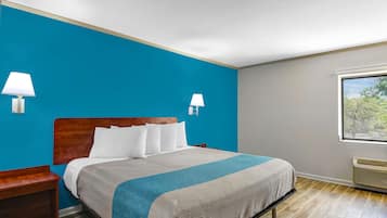 A hotel room with a bed, nightstand, two wall-mounted lamps, a window with a view, and a built-in heater.