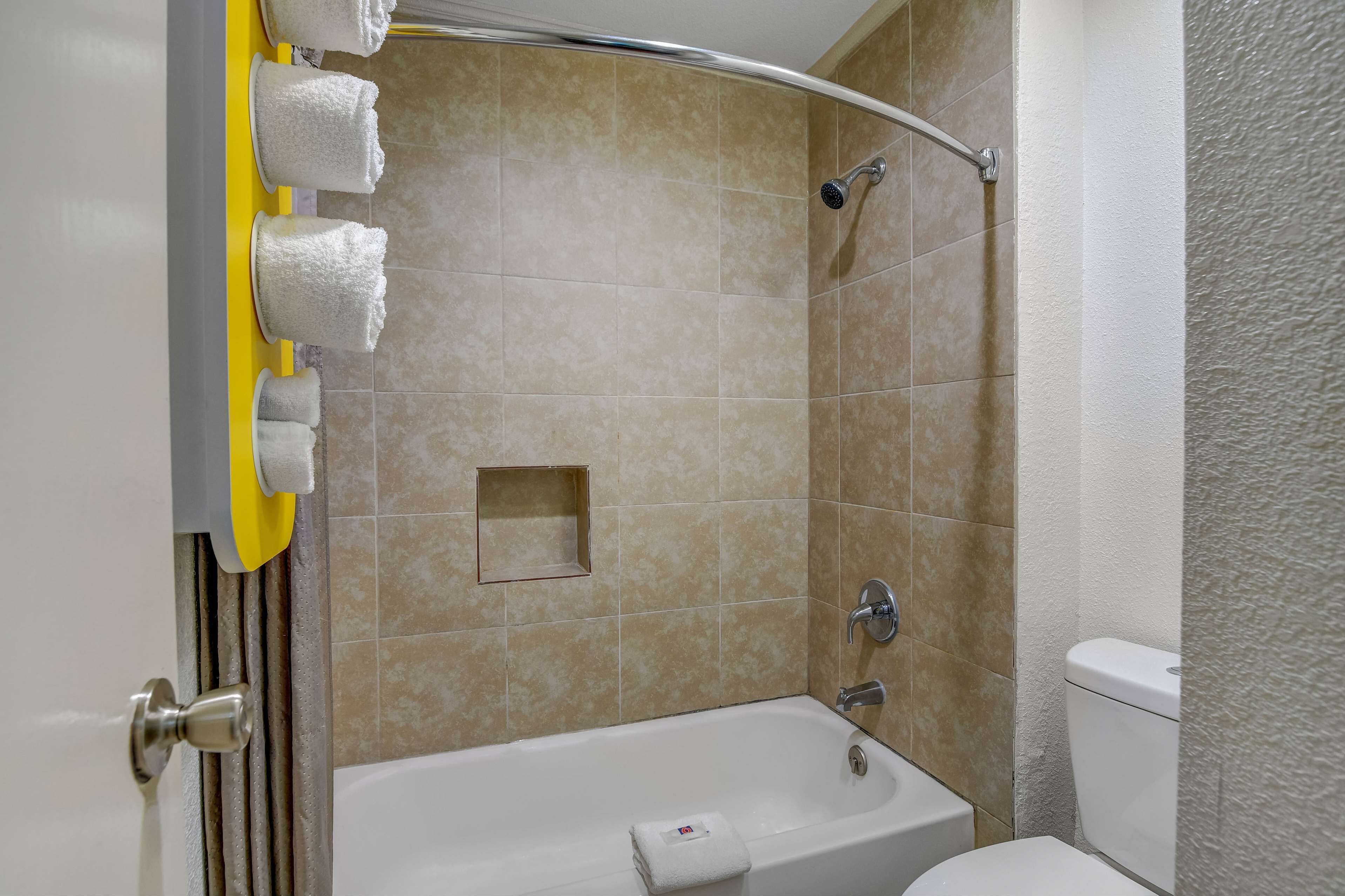 A bathroom with a bathtub, a shower, and a toilet. There are towels hanging on a rack.