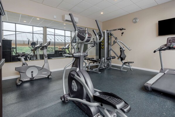 A gym with various exercise equipment, large windows, and a clock on the wall. - Best Western Plus Poconos Hotel (Tannersville)