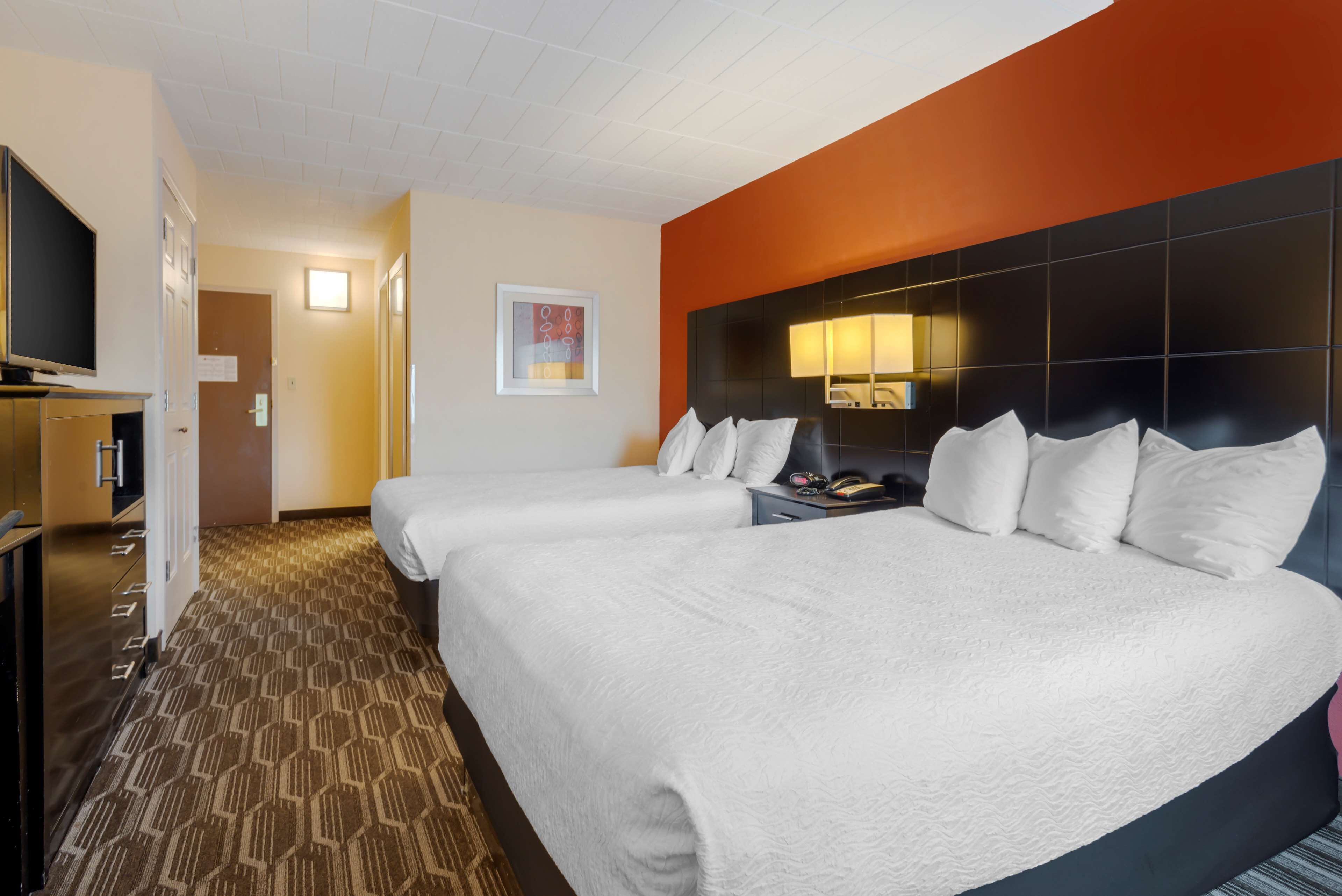 A hotel room with two beds, a TV, a desk, and a lamp.