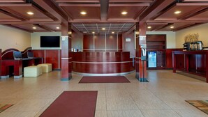 Un área de recepción con un mostrador curvo, asientos, un televisor de pantalla plana y una máquina expendedora.
