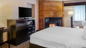 Habitación de hotel con cama, televisión en una cómoda, chimenea y escritorio con silla.