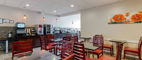 Un restaurante con una decoración moderna, que incluye una zona de cocina, mesas para comer y sillas rojas.