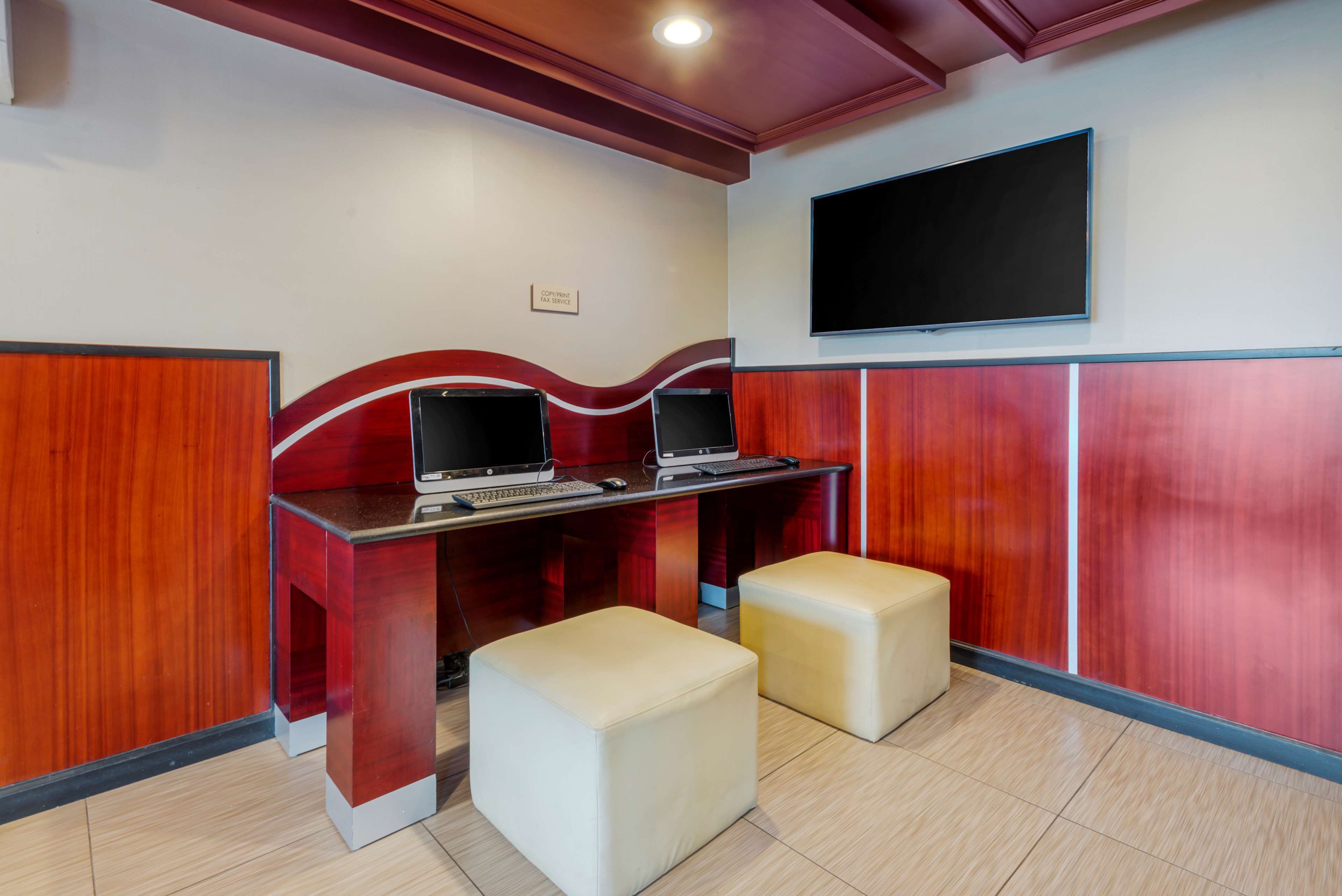 A reception area with a wooden desk, two computers, a flat-screen TV, and two cushioned seating areas.
