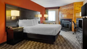 Una habitación de hotel con una cama grande, una mesita de noche, un televisor y una chimenea.
