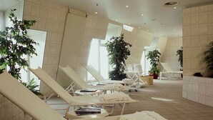 Un espacio de spa con sillones reclinables, toallas y plantas en macetas.