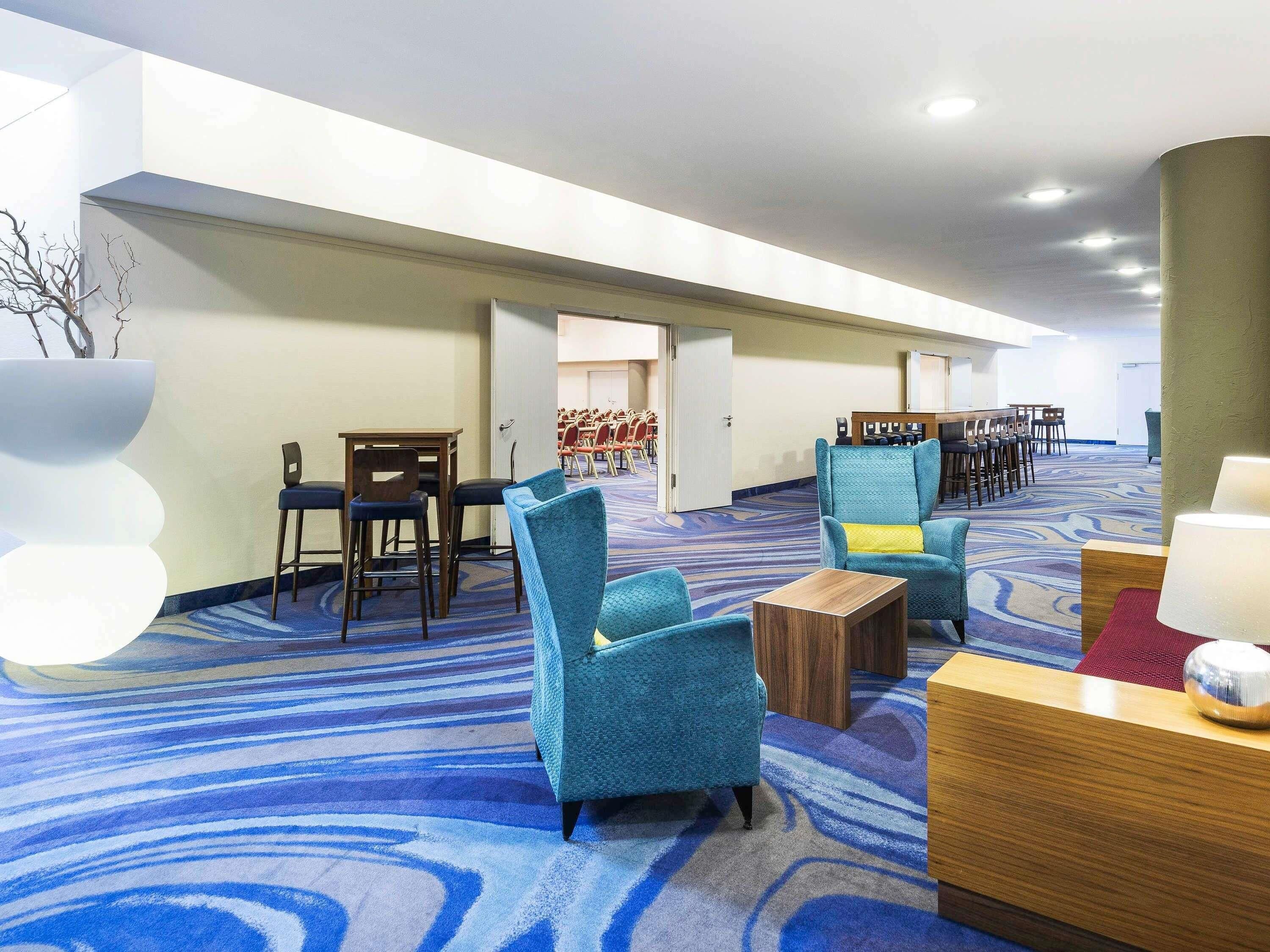 A hotel lobby with seating areas, a reception desk, and a patterned carpet.