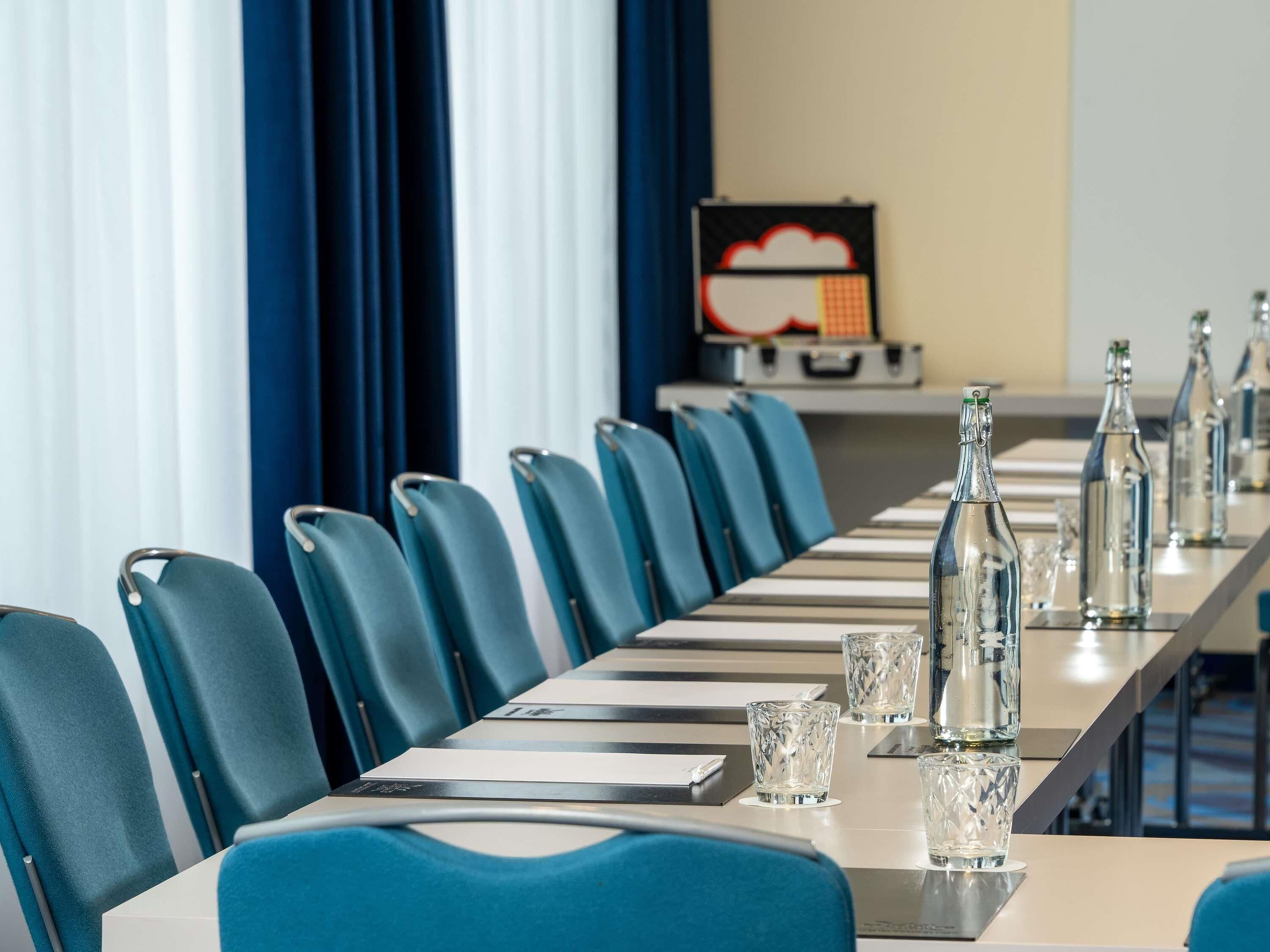 A conference room with a long table, chairs, and water bottles.