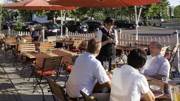 Outdoor seating with tables and chairs, umbrellas, and a white picket fence in the background.