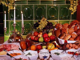 Un bufé con diversos alimentos, entre ellos frutas, pan y queso.