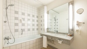 Une salle de bain moderne avec une baignoire, une douche et un grand miroir.