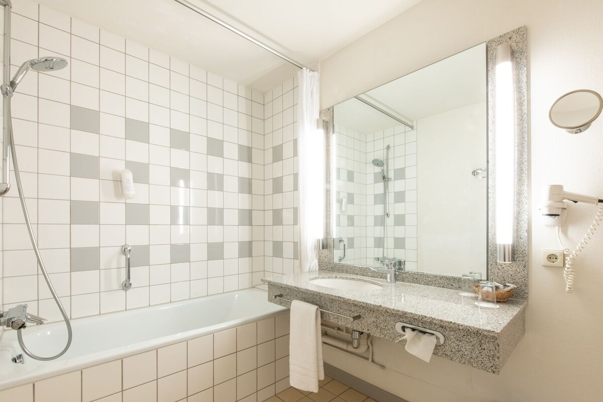 Une salle de bain moderne avec une baignoire, une douche et un grand miroir.
