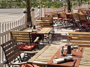 An outdoor dining area with wooden tables and chairs, arranged in rows. - Mercure Hotel Offenburg am Messeplatz (Offenburg)