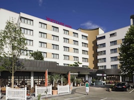 Un hotel con fachada blanca, numerosas ventanas y un cartel que dice 'Mercure Hotel'.