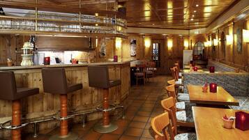Un restaurante con interiores de madera, taburetes, mesas y una zona de bar con vasos.
