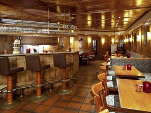 A restaurant with wooden interiors, bar stools, tables, and a bar area with glasses. - Mercure Hotel Offenburg am Messeplatz (Offenburg)