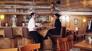 A bar area with wooden furniture, a counter with bottles, and glasses. - Mercure Hotel Offenburg am Messeplatz (Offenburg)