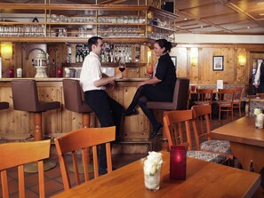 A bar area with wooden furniture, a counter with bottles, and glasses. - Mercure Hotel Offenburg am Messeplatz (Offenburg)
