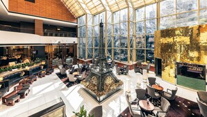 Een ruime lobby met een hoge plafond, een centraal decoratief element en grote ramen met uitzicht op de omgeving.