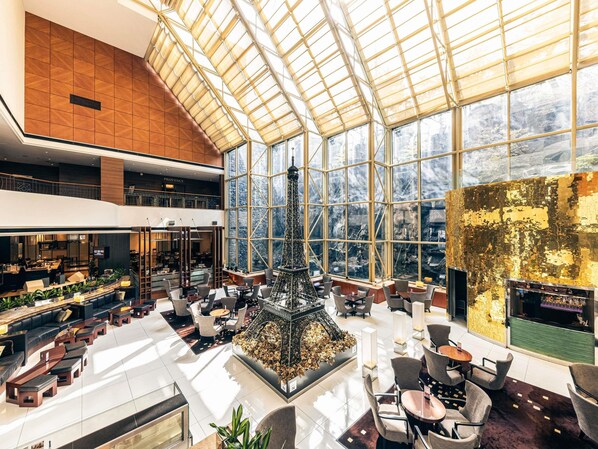 A spacious lobby with a high ceiling, a central decorative structure, and large windows offering views of the outdoors.