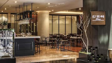 Un intérieur de restaurant moderne avec un îlot central, des tables et des chaises disposées de manière harmonieuse, et un arbre décoratif.