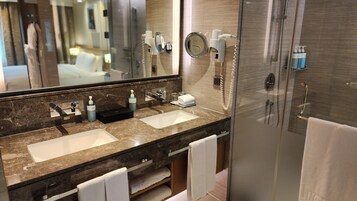 A bathroom with two sinks, a mirror, a towel rack, and a shower.