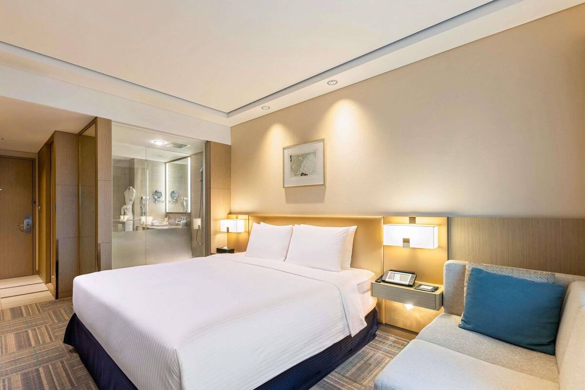 Une chambre d’hôtel avec un grand lit, une table de chevet, une lampe et un canapé.