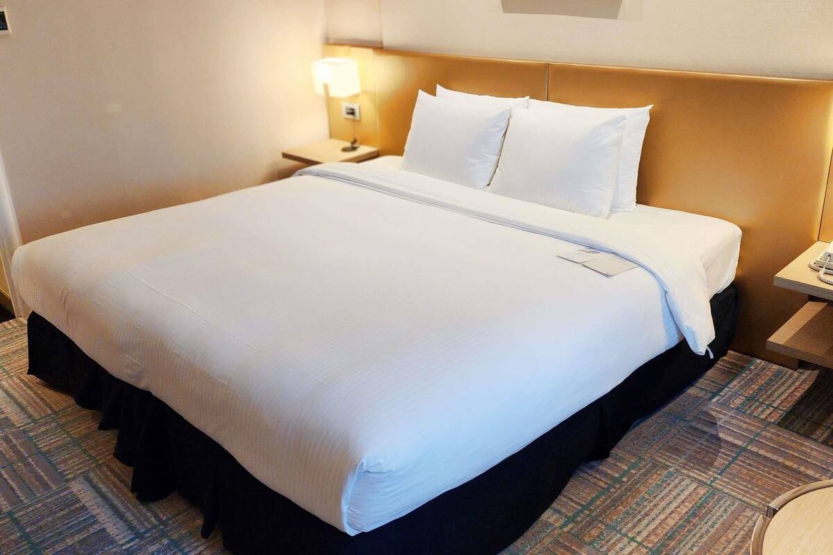 Une chambre d’hôtel avec un grand lit, une table de chevet avec une lampe et un tableau encadré au mur.
