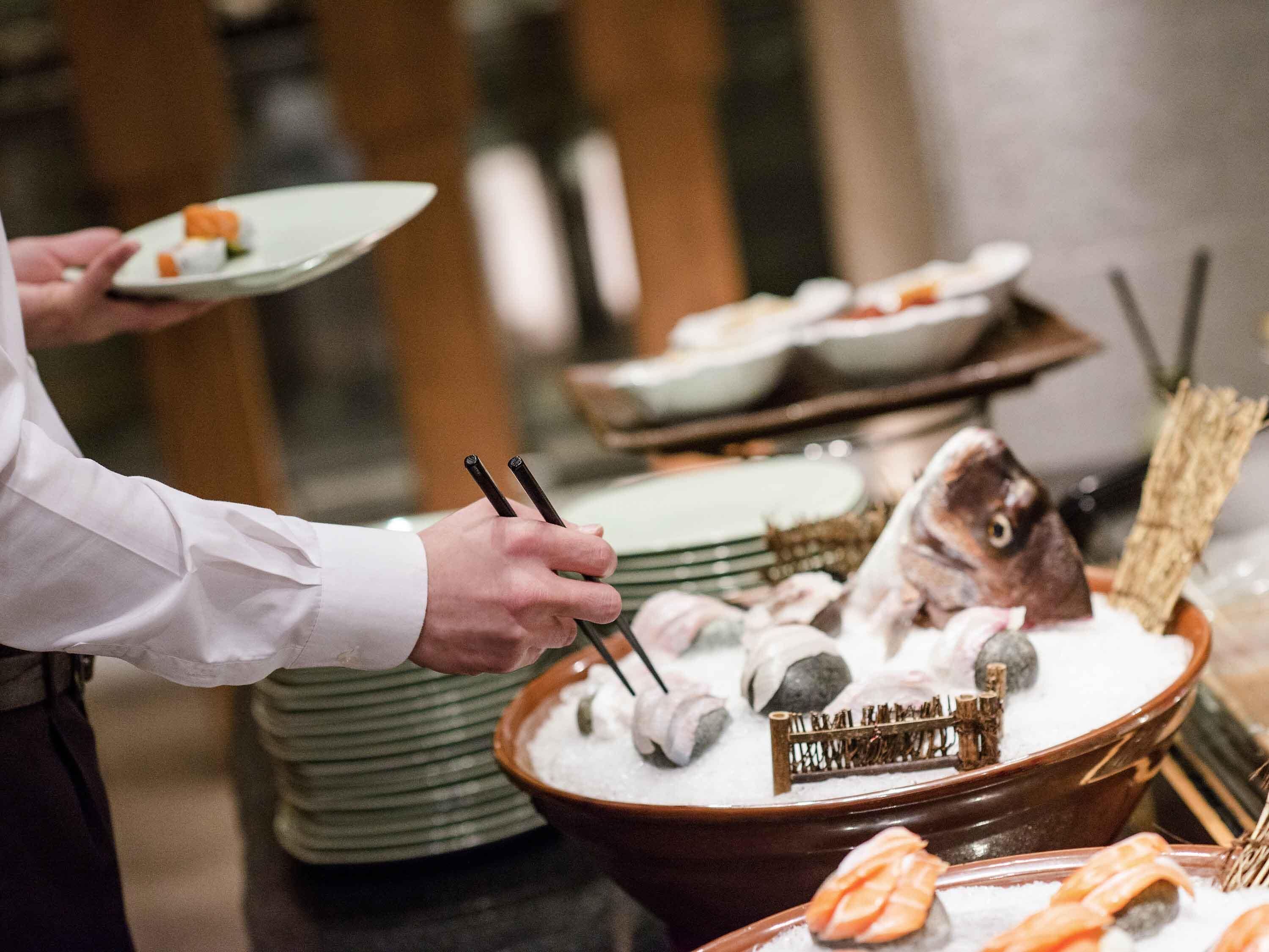 A buffet setup with seafood, including salmon and sushi, and a fish head decoration.