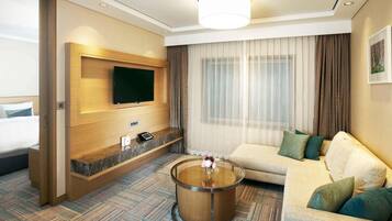 A hotel room with a bed, a sofa, a coffee table, a TV mounted on the wall, and a large window with curtains.