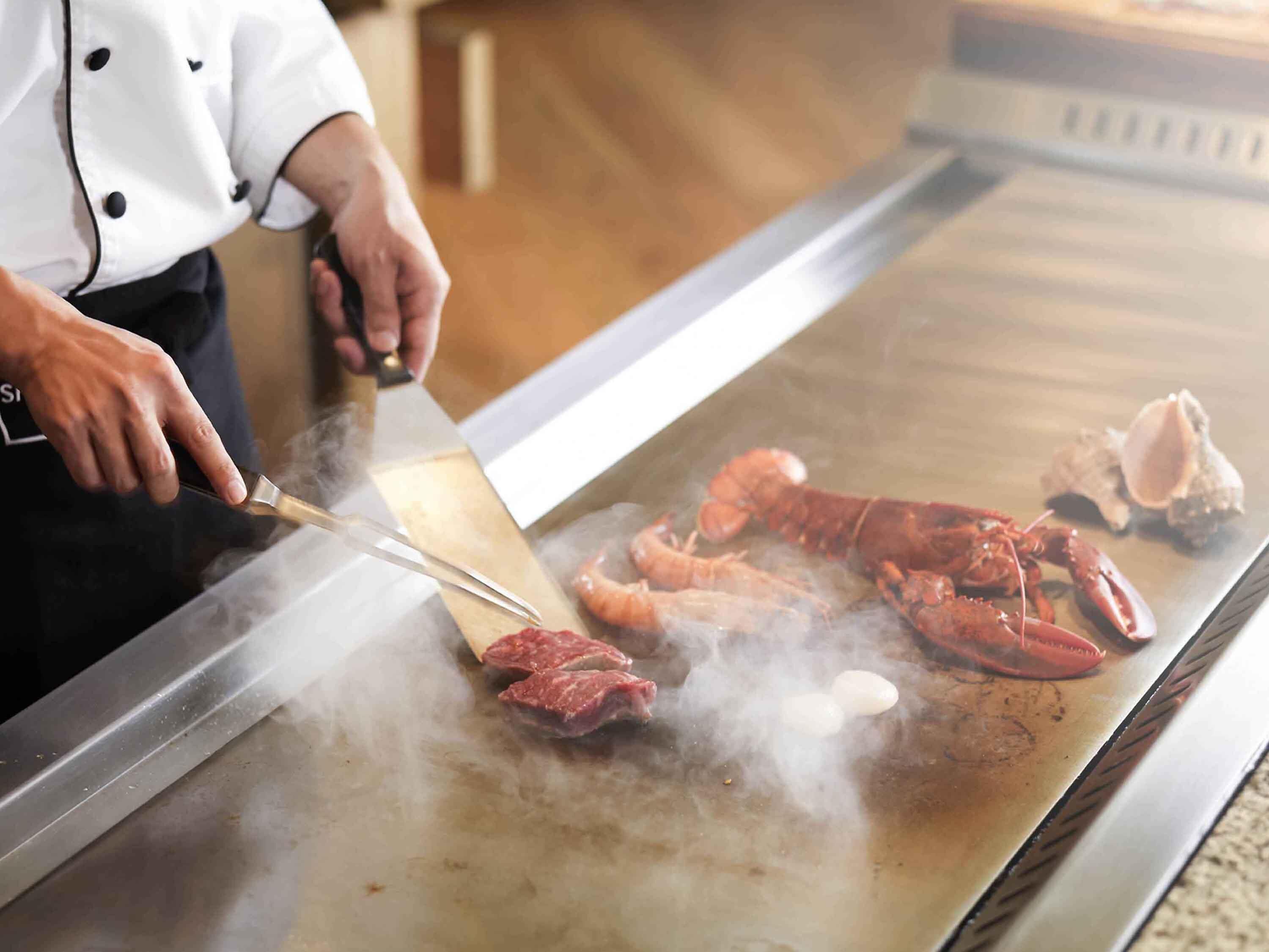 Un chef asando langosta sobre una plancha.