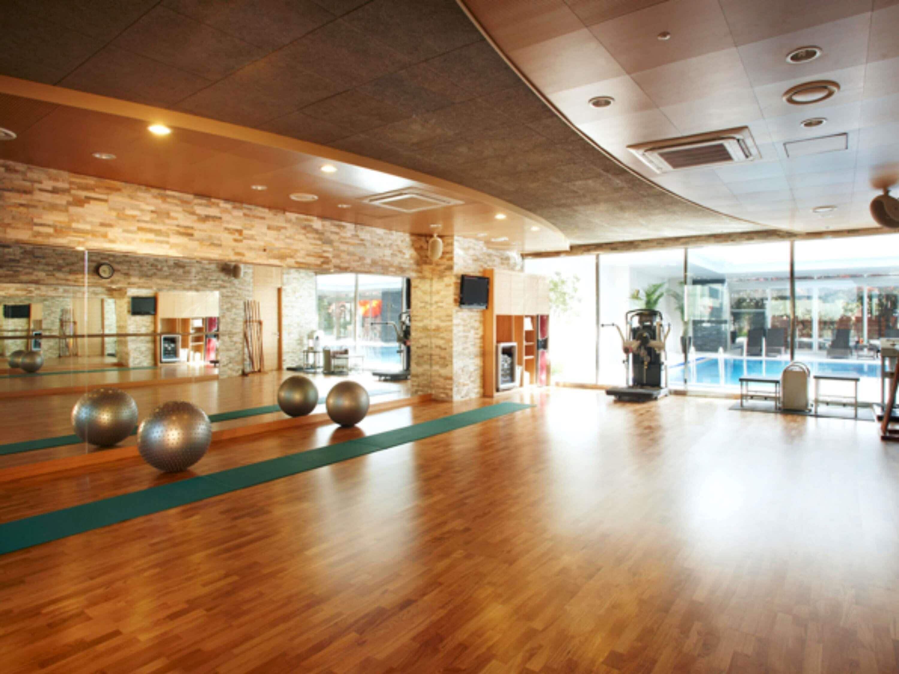 A spacious indoor area with a wooden floor, a large mirror, and exercise equipment.