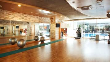 A spacious indoor area with a wooden floor, a large mirror, and exercise equipment.