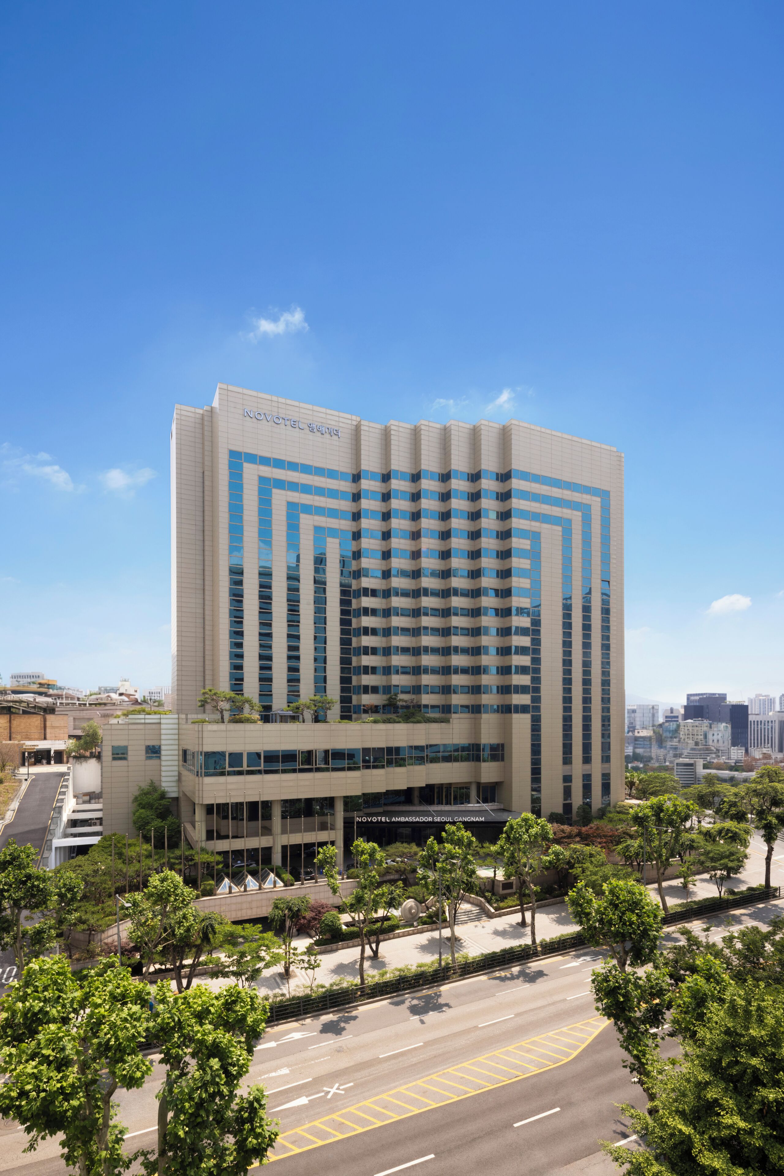 A modern hotel building with a prominent entrance, multiple floors, and a clear sky.