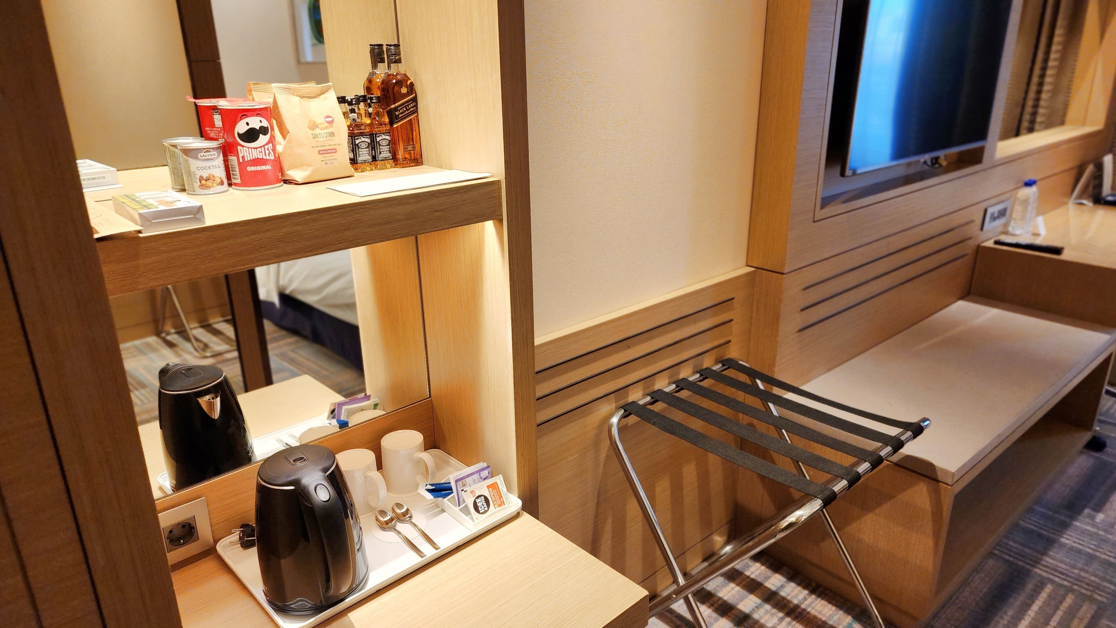 Een hotelkamer met een kitchenette, televisie, bed en raam.