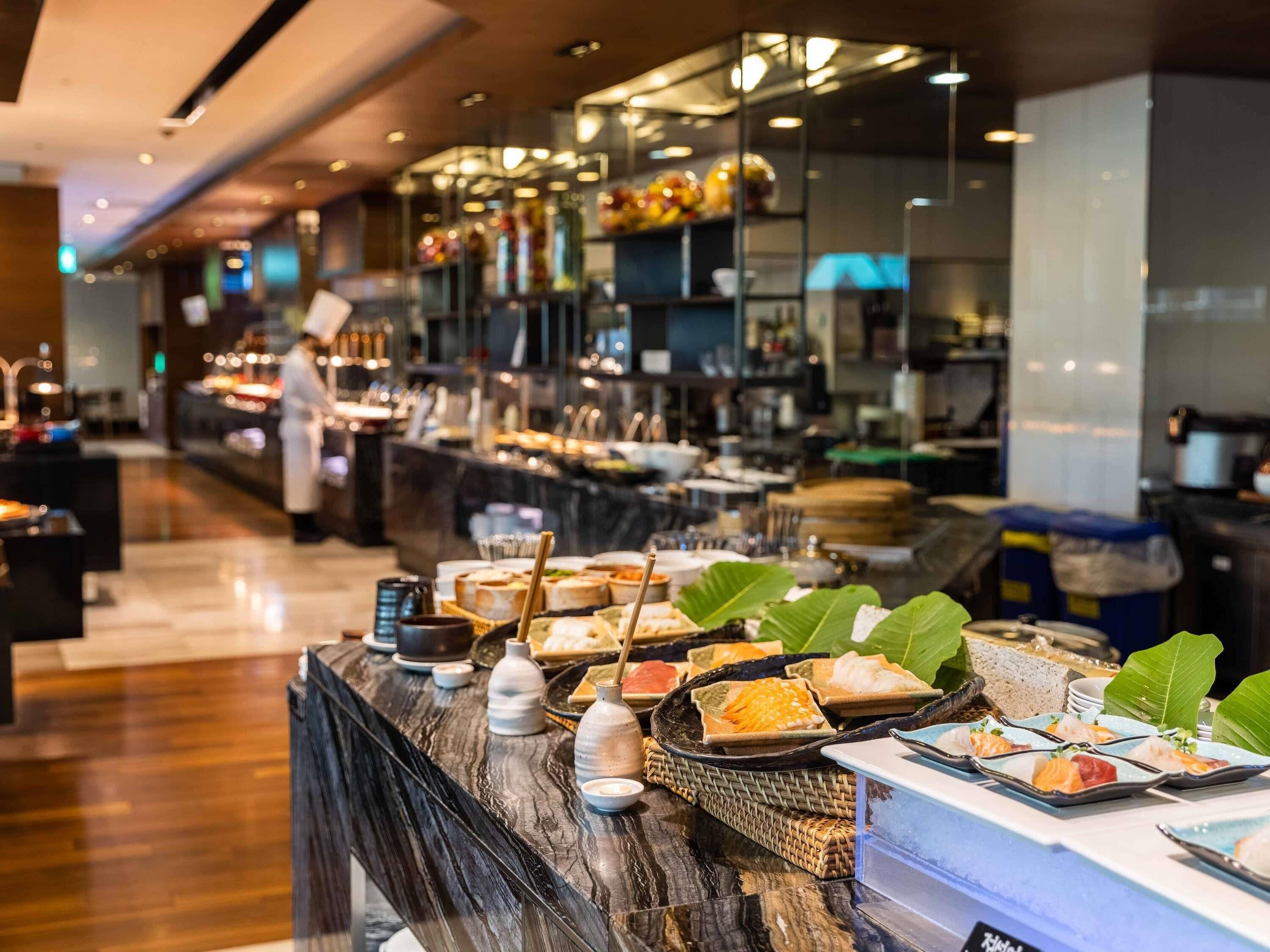 Un espace buffet proposant divers plats, avec un chef cuisinier en arrière-plan.