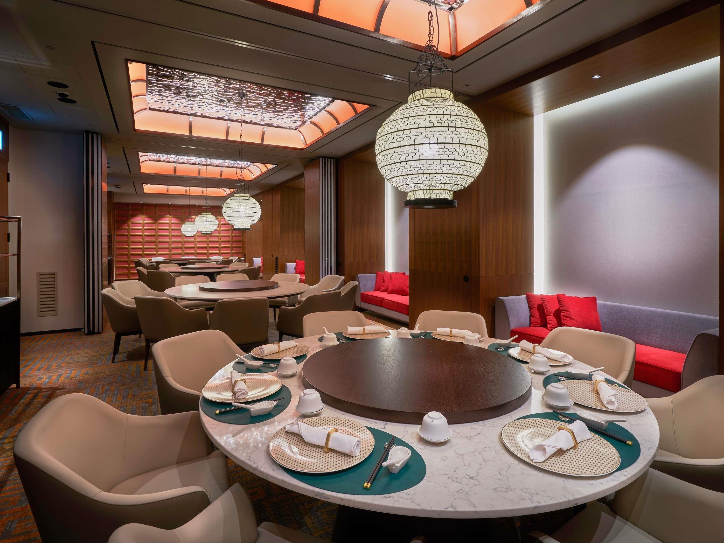A modern dining area with round tables, chairs, and a central decorative piece.