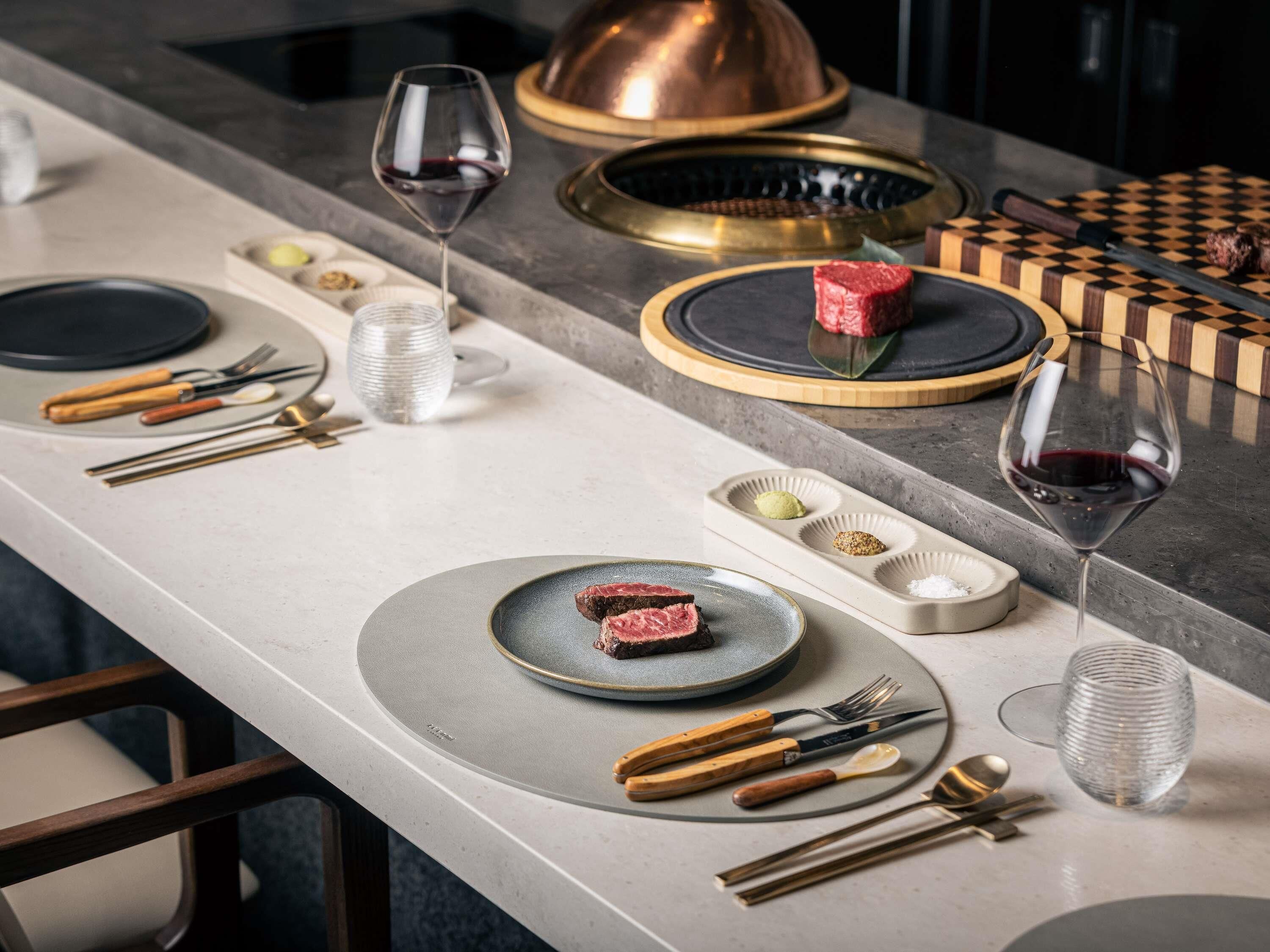 Une table à manger dressée avec des assiettes, des couverts, des verres et un centre de table décoratif.